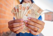 Uma pessoa segurando cédulas de 50 reais.