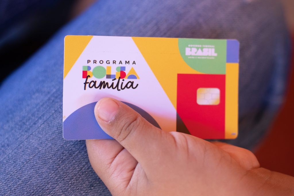 O Bolsa Família é um dos principais programas de transferência de renda no Brasil, destinado a apoiar famílias em situação de vulnerabilidade econômica.
Recentemente, um estudo realizado pelo Serviço Brasileiro de Apoio às Micro e Pequenas Empresas (Sebrae), em colaboração com o Ministério do Desenvolvimento e Assistência Social, Família e Combate à Fome (MDS), trouxe novas perspectivas sobre a relação entre o Bolsa Família e o Microempreendedor Individual (MEI).
Esse estudo revelou que aproximadamente 30% dos microempreendedores individuais no Brasil estão registrados no Cadastro Único de Programas Sociais do Governo Federal (CadÚnico), sistema essencial para a concessão de benefícios sociais como o Bolsa Família.
Microempreendedores Individuais no CadÚnico
Entre os microempreendedores individuais inscritos no CadÚnico, 52% se formalizaram após a inscrição em programas de inclusão social.
Os dados também mostram uma predominância feminina, com mulheres representando 55% dos inscritos, o que equivale a cerca de 2,5 milhões de pessoas, comparado a 45% de homens, ou dois milhões de cidadãos.
Além disso, 42,5% desses MEIs ainda não têm rendimentos regulares, e apenas 16% recebem mais de um salário mínimo, equivalente a R$ 1.412. Esses números ilustram a importância do Bolsa Família e do microempreendedorismo na luta contra a pobreza.
O papel do Cadastro Único e do Bolsa Família
O Cadastro Único (CadÚnico) é a ferramenta principal para identificar e caracterizar as famílias de baixa renda no Brasil.
Ele permite a inclusão de famílias com renda mensal por pessoa de até meio salário mínimo, ou aquelas que estejam aguardando algum benefício social.
Dessa forma, é comum que microempreendedores individuais estejam registrados no CadÚnico e, consequentemente, sejam beneficiários do Bolsa Família.
Microempreendedor Individual (MEI) e Bolsa Família: é possível receber ambos?
Sim, é possível que um microempreendedor individual (MEI) continue a receber o Bolsa Família. Para isso, o MEI deve estar inscrito no CadÚnico e ter uma renda familiar per capita de até R$ 218.
Vale destacar que a formalização como MEI não resulta automaticamente na perda do benefício, desde que os critérios de renda sejam respeitados.
Assim, mesmo com um aumento na renda familiar devido ao trabalho como MEI, o beneficiário pode manter o Bolsa Família enquanto a renda per capita se mantiver dentro dos limites estabelecidos.
O aumento de renda na manutenção do benefício
Embora a formalização e o aumento de renda possam influenciar a elegibilidade para o Bolsa Família, a regra não implica na exclusão imediata do programa.
Se o rendimento mensal da família aumentar, o programa adota uma regra de transição, levando em conta os novos limites de renda.
O objetivo é garantir que o impacto financeiro da transição para uma nova faixa de renda não resulte em uma perda abrupta do benefício.
Quem pode se inscrever no Bolsa Família?
Para se inscrever no Bolsa Família, as famílias devem atender a critérios específicos de renda e composição familiar. A principal exigência é que a renda per capita da família seja de até R$ 218.
Isso significa que a soma dos rendimentos de todos os membros da família deve ser dividida pelo número total de pessoas, e o valor obtido deve ser inferior ao teto estabelecido.
Além disso, o Cadastro Único (CadÚnico) é um pré-requisito essencial para a inscrição, pois é através dele que o governo federal identifica e avalia a situação socioeconômica das famílias.
Como se inscrever no Bolsa Família?
A inscrição no Bolsa Família pode ser realizada em um dos Centros de Referência de Assistência Social (CRAS) do município, que são os pontos de atendimento aos cidadãos para acesso a programas sociais.
Para efetuar a inscrição, é necessário que a família esteja registrada no CadÚnico, que é o sistema utilizado pelo governo para gerir os benefícios sociais.
Após a inscrição e a aprovação, a família receberá um cartão da Caixa Econômica Federal, que permitirá o acesso ao benefício.
Além disso, um panfleto informativo é enviado junto com o cartão, detalhando como acessar os valores, as datas de pagamento e outras informações importantes.
Contrapartidas e condições para recebimento do benefício
Os beneficiários do Bolsa Família devem cumprir certas contrapartidas para manter o recebimento do benefício. Essas exigências são voltadas para promover a educação e a saúde das crianças e adolescentes, além de garantir o acompanhamento das gestantes.
As principais contrapartidas incluem: manter crianças e adolescentes matriculados e frequentando a escola, realizar acompanhamento pré-natal para gestantes, e manter as carteiras de vacinação das crianças atualizadas.
Essas condições são essenciais para garantir que o apoio financeiro do Bolsa Família contribua efetivamente para a melhoria das condições de vida e saúde dos beneficiários.
Benefícios adicionais e valores do Bolsa Família
O Bolsa Família oferece um valor mínimo de R$ 600 por família, que pode ser complementado com adicionais conforme a composição familiar.
Há um valor extra de R$ 150 por cada criança de até 6 anos, e R$ 50 por gestantes e por crianças e adolescentes de 7 a 17 anos. Além disso, é concedido um suplemento de R$ 50 por bebês de até seis meses.
Esses valores são ajustados de acordo com as necessidades específicas da família, ajudando a cobrir despesas relacionadas à educação, saúde e cuidados básicos dos filhos.
O Bolsa Família continua sendo uma ferramenta crucial para o apoio às famílias em situação de vulnerabilidade, mesmo para aquelas que se formalizam como microempreendedores individuais. A manutenção do benefício está sujeita ao cumprimento das regras de renda e à inscrição no CadÚnico.
O estudo do Sebrae e do MDS destaca a importância de apoiar microempreendedores e de garantir que a inclusão econômica não comprometa o acesso a benefícios essenciais.
A combinação de assistência social e empreendedorismo representa uma estratégia eficaz para reduzir a pobreza e promover o desenvolvimento econômico sustentável no Brasil.