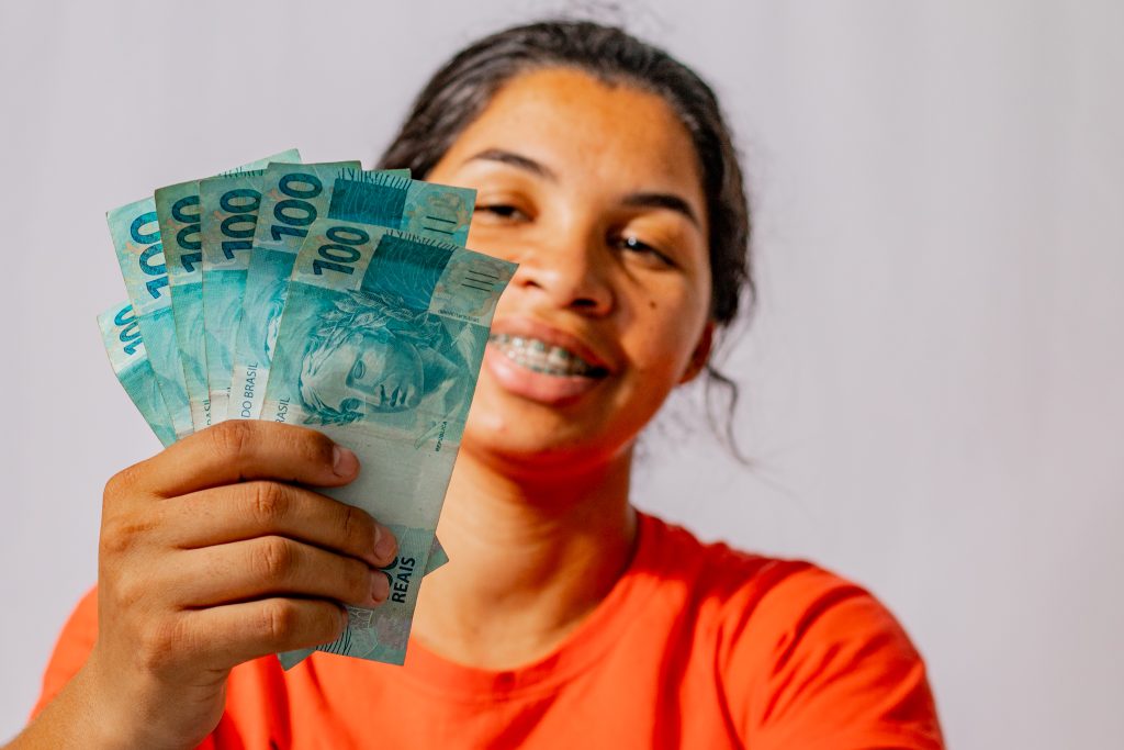 Mulher com notas de 100 reais na mão. 