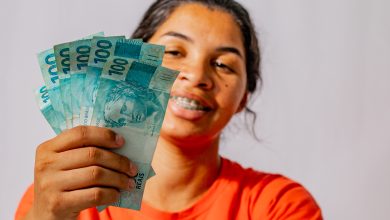 Mulher com notas de 100 reais na mão.