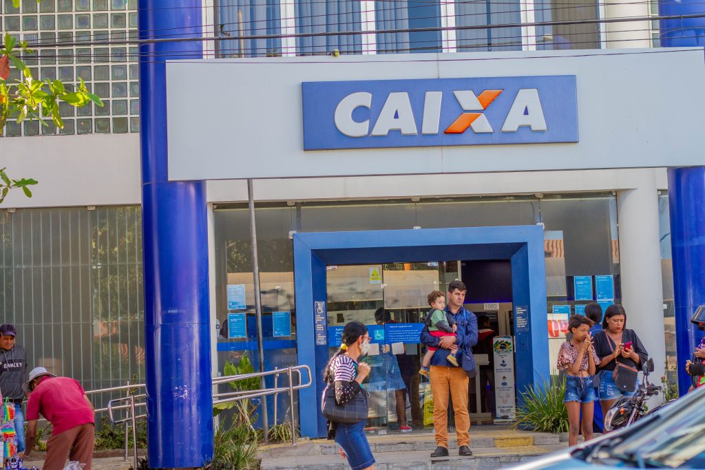 Pessoas em frente ao banco Caixa. 