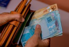 Mulher guardando dinheiro na carteira.