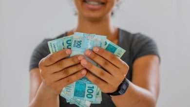 Mulher com 100 reais na mão.