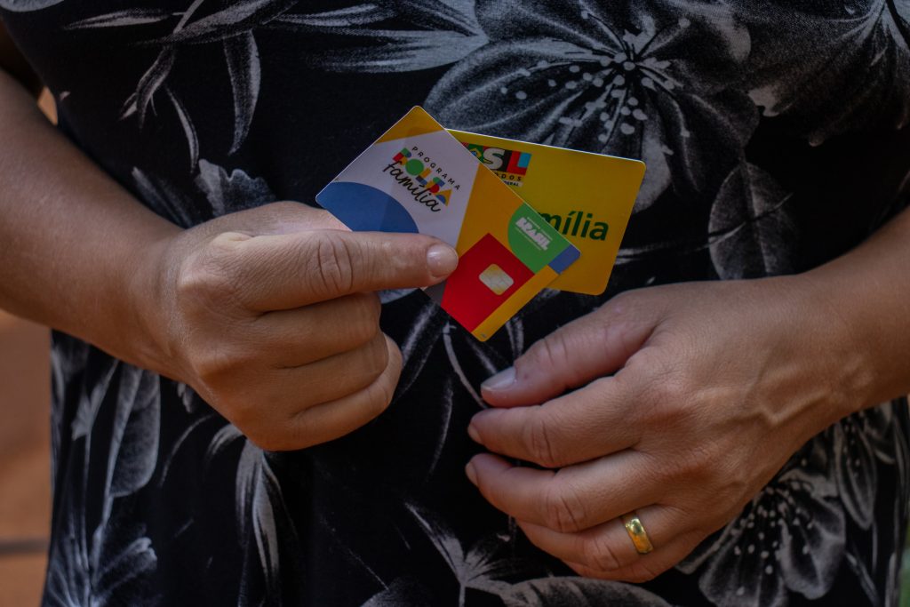 Mulher segurando cartão Bolsa Família. 