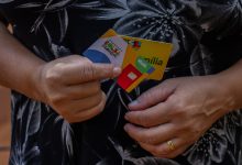 Mulher segurando cartão Bolsa Família.