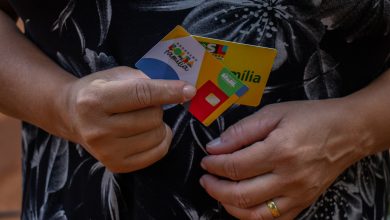 Mulher segurando cartão Bolsa Família.