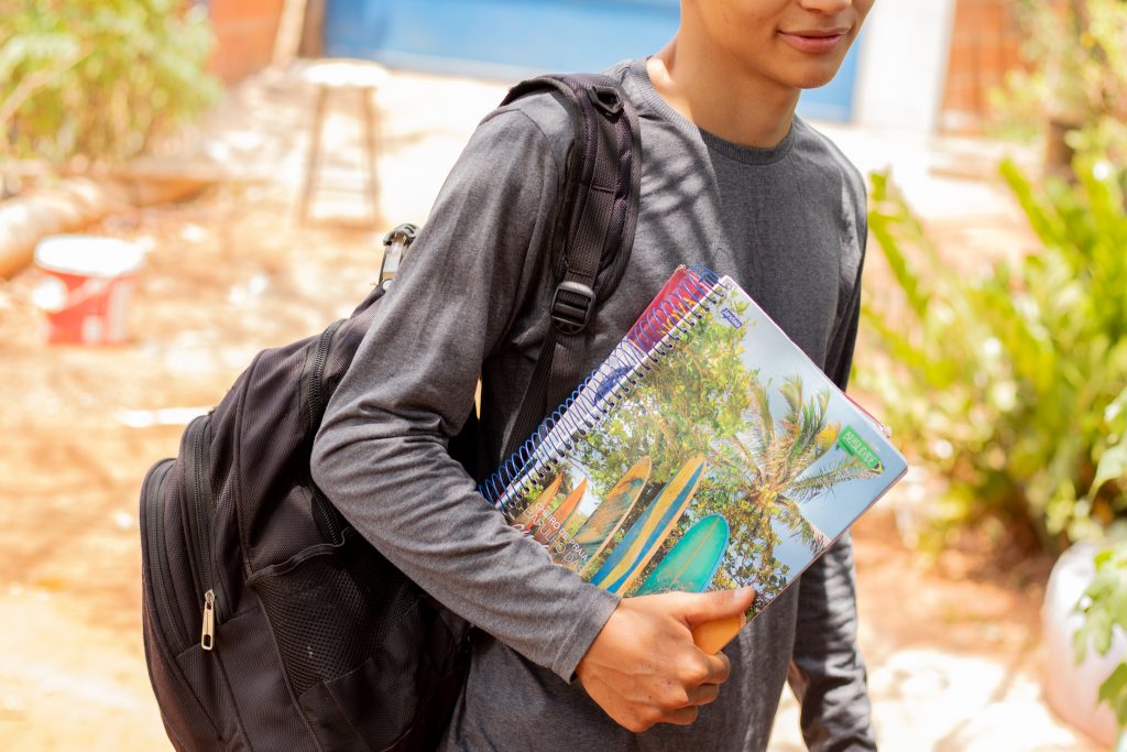 Estudante indo para a escola com livros na mão. 