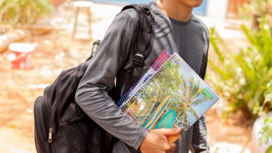 Estudante indo para a escola com livros na mão.