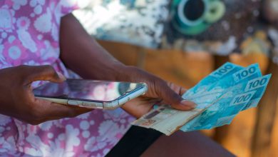 Mulher com celular na mão ganhando dinheiro.