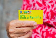 Mulher segurando cartão bolsa família.