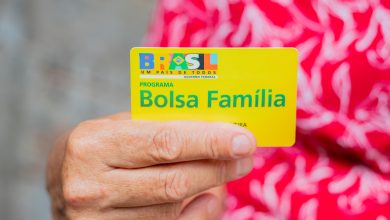 Mulher segurando cartão bolsa família.