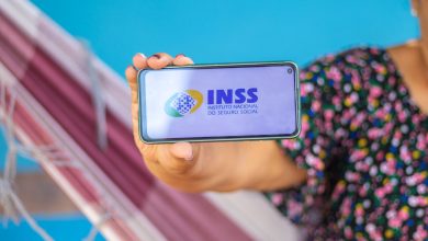 Mulher segurando celular com app INSS.