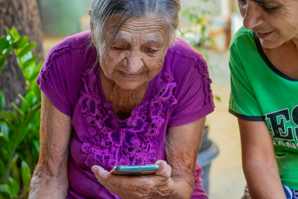 Duas senhoras de idade mexendo no celular.